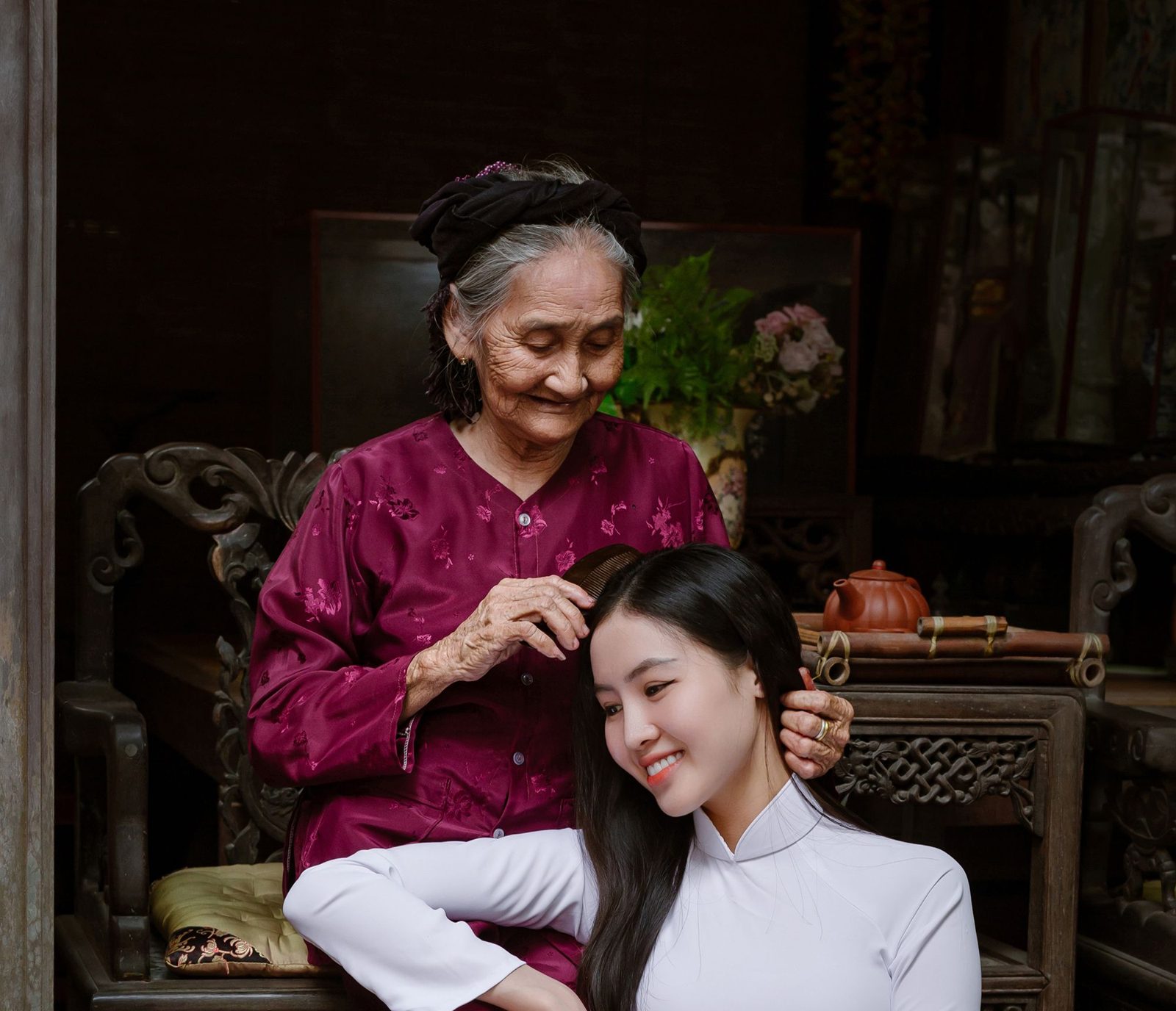 Bà cụ người Việt chải tóc cho cháu gái mặc áo dài